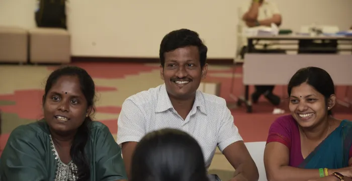 Group of participants, 1 man, and 3 women are seated around a table, engaged in a discussion